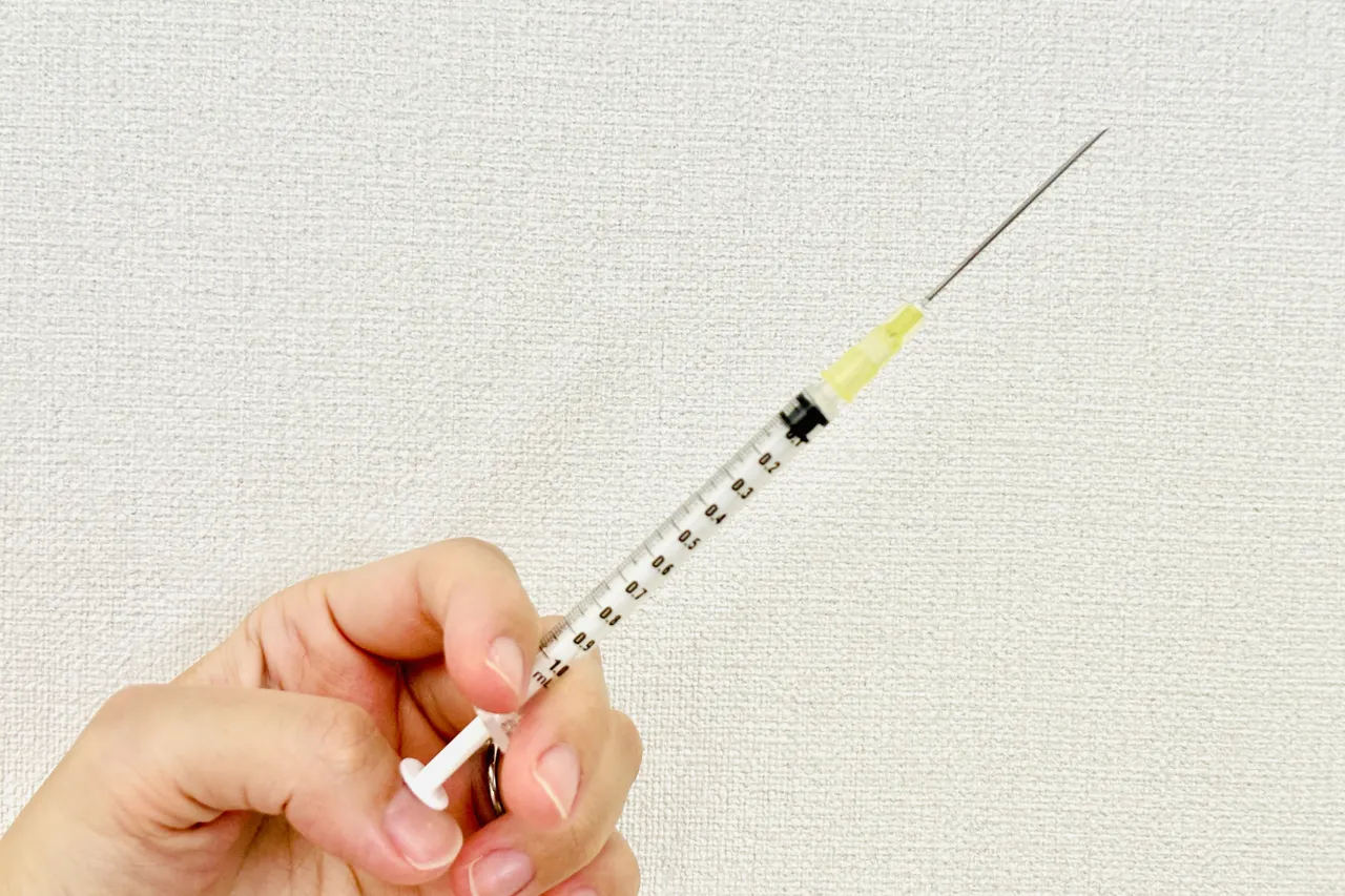 細い注射針の付いた注射器を持つ手