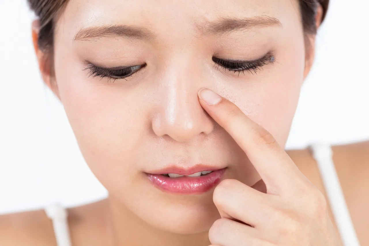 小鼻に指を当てる女性