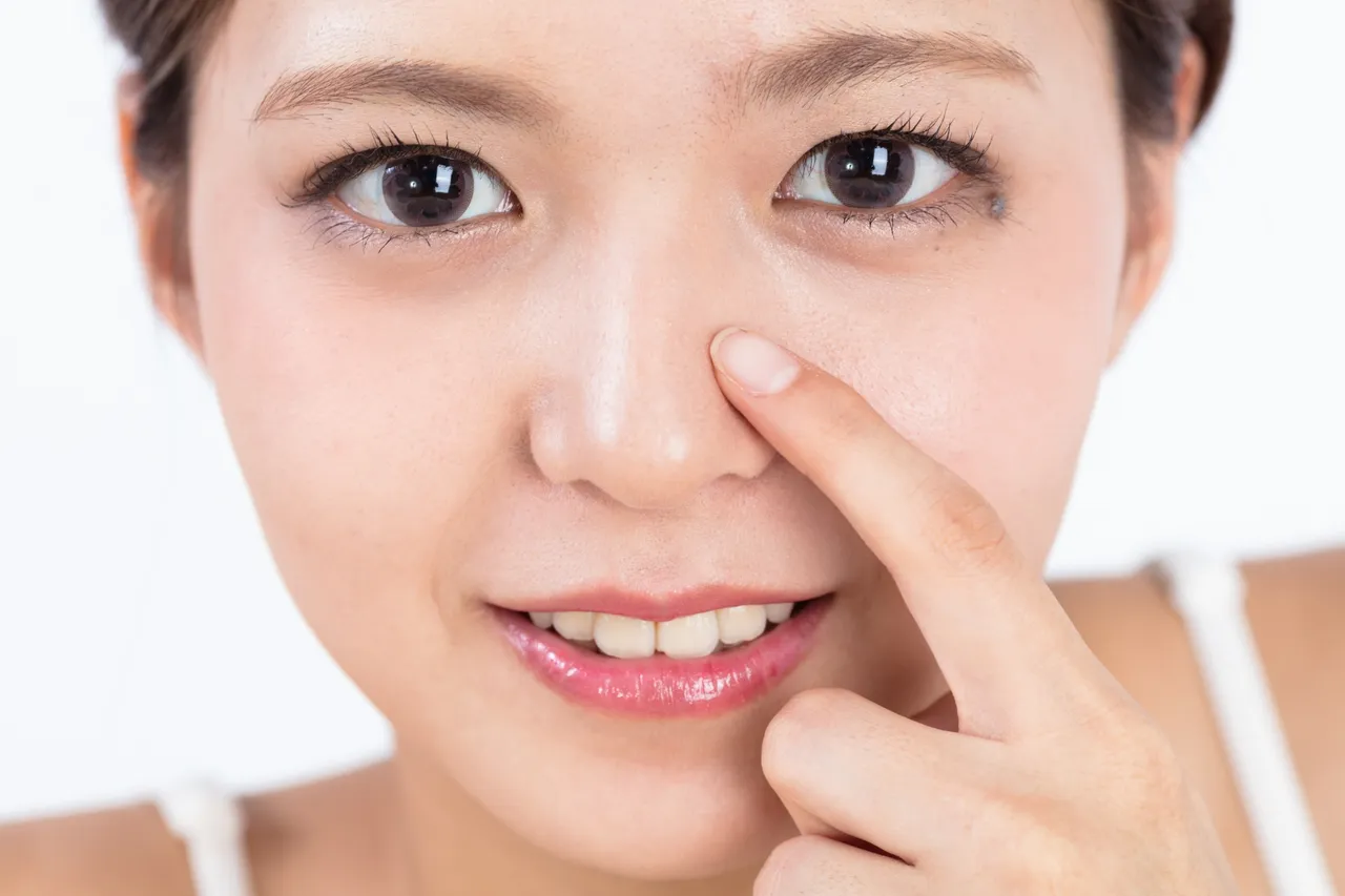 小鼻に指を当てて笑う女性
