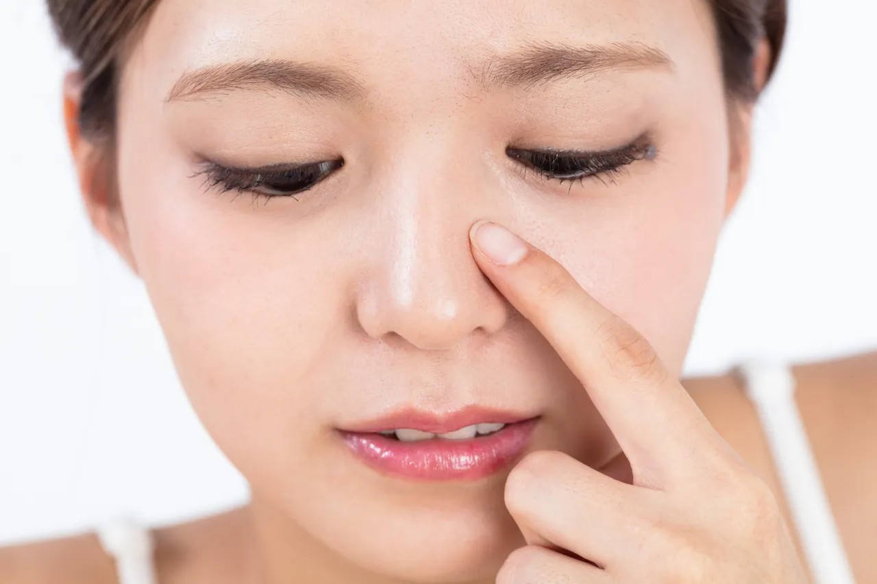 小鼻に指を添えた女性の顔