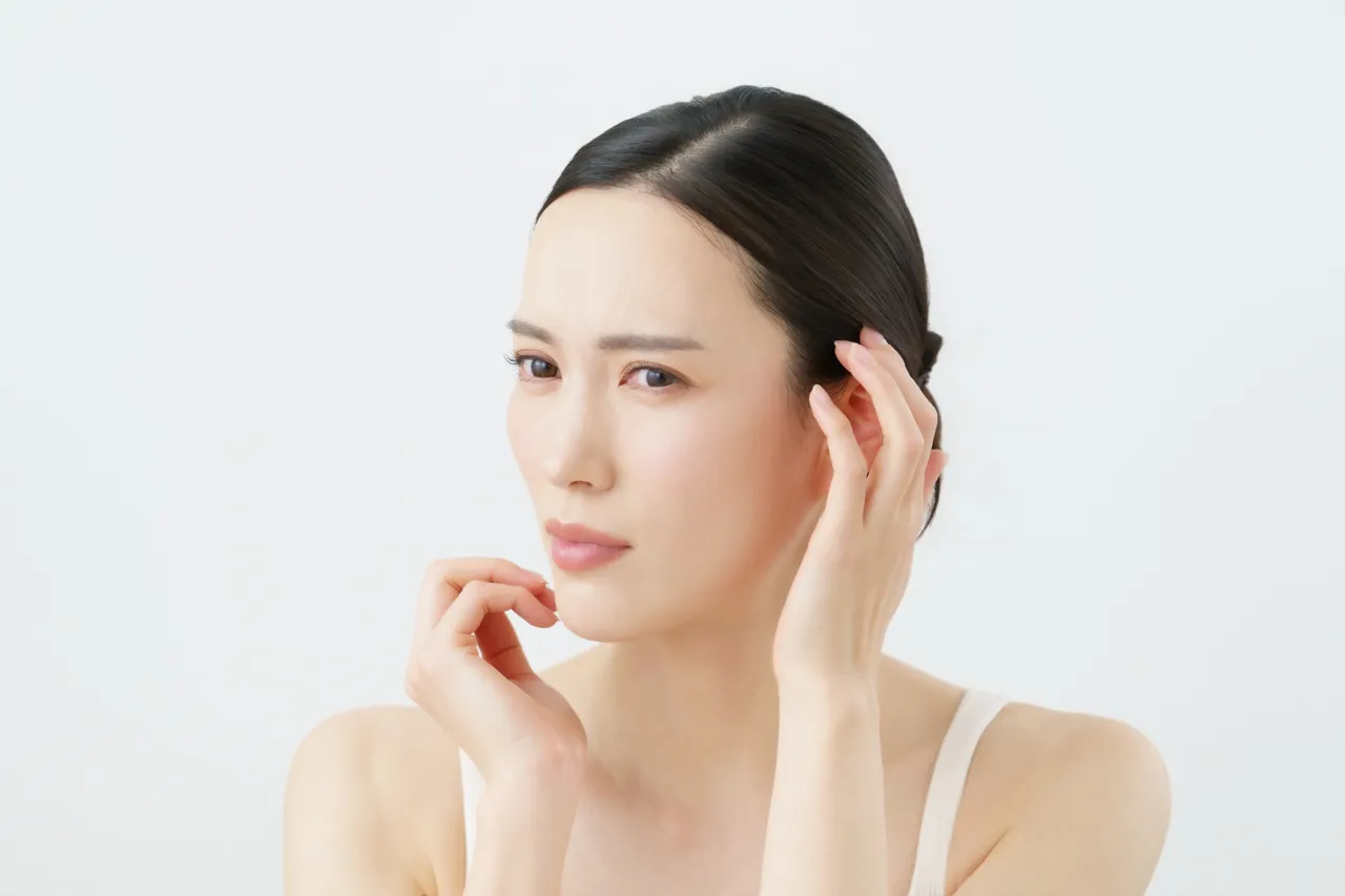 顔に手を当てて違和感を気にする女性