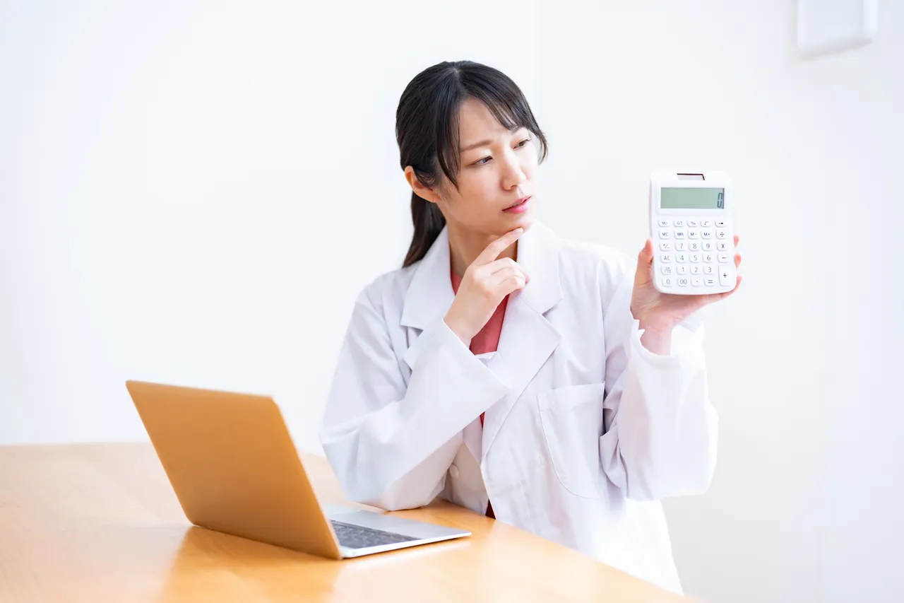 電卓を手に料金を確かめる女性医師