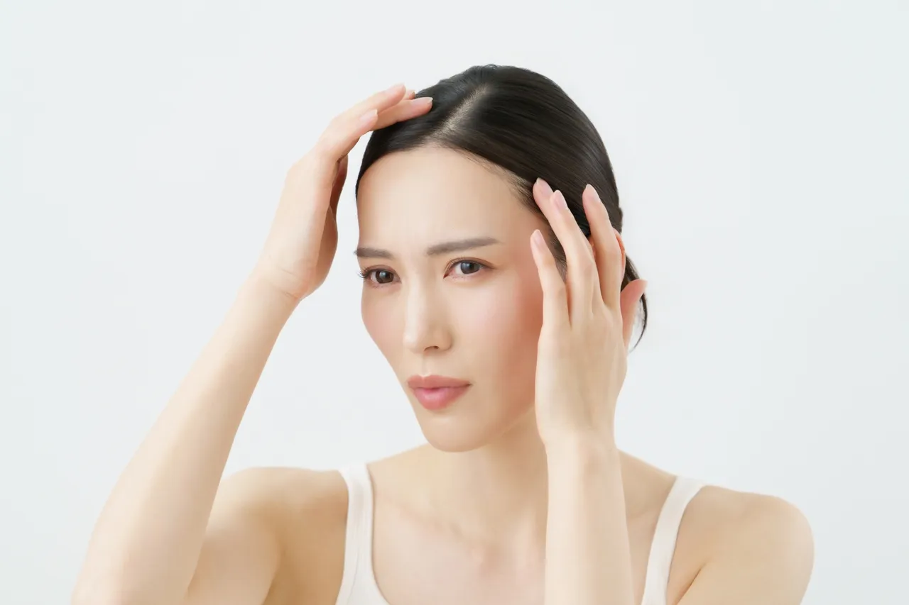 不安そうな表情で顔に手を当てる女性