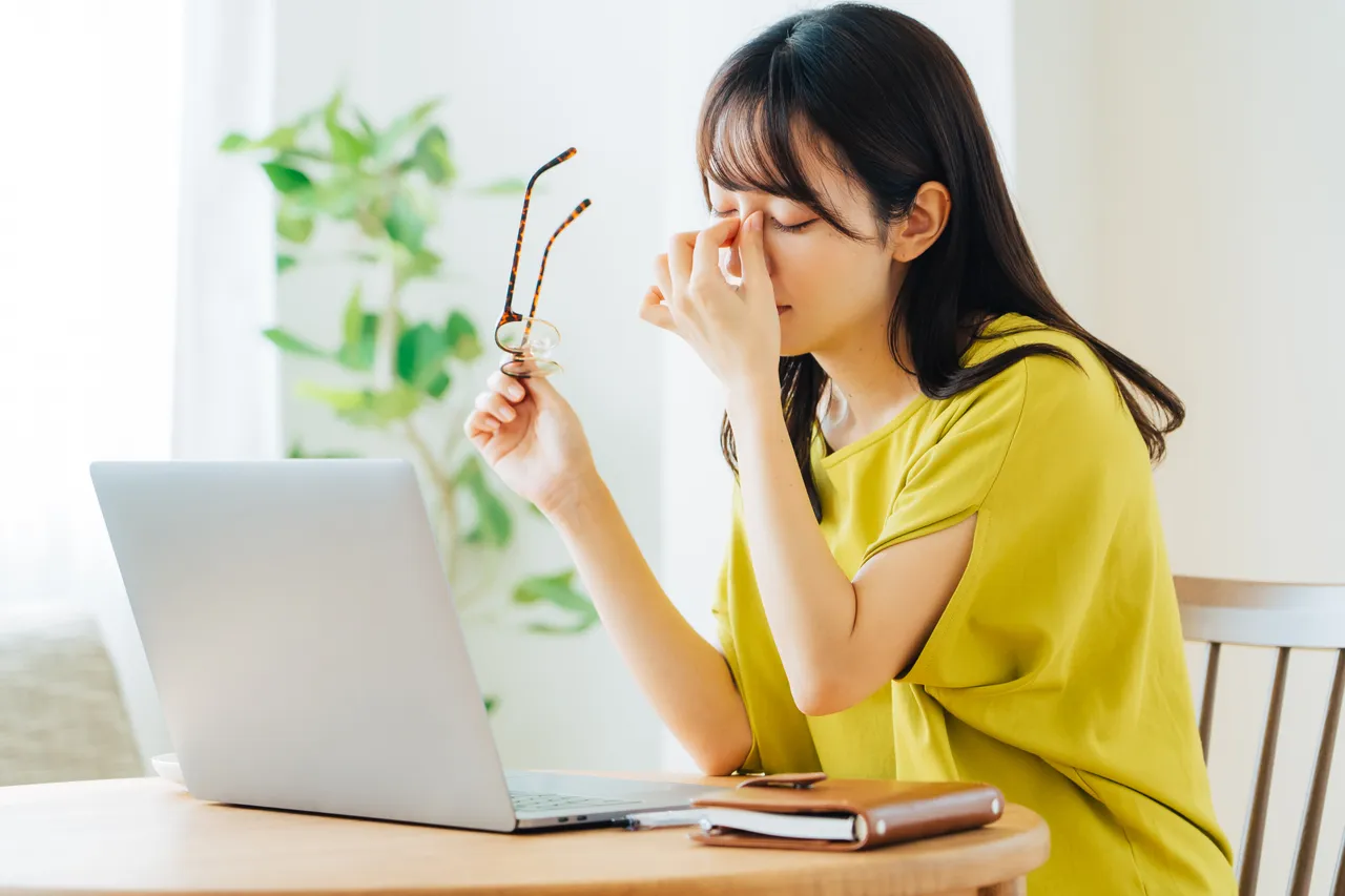 眼鏡を外して目元を押さえる女性