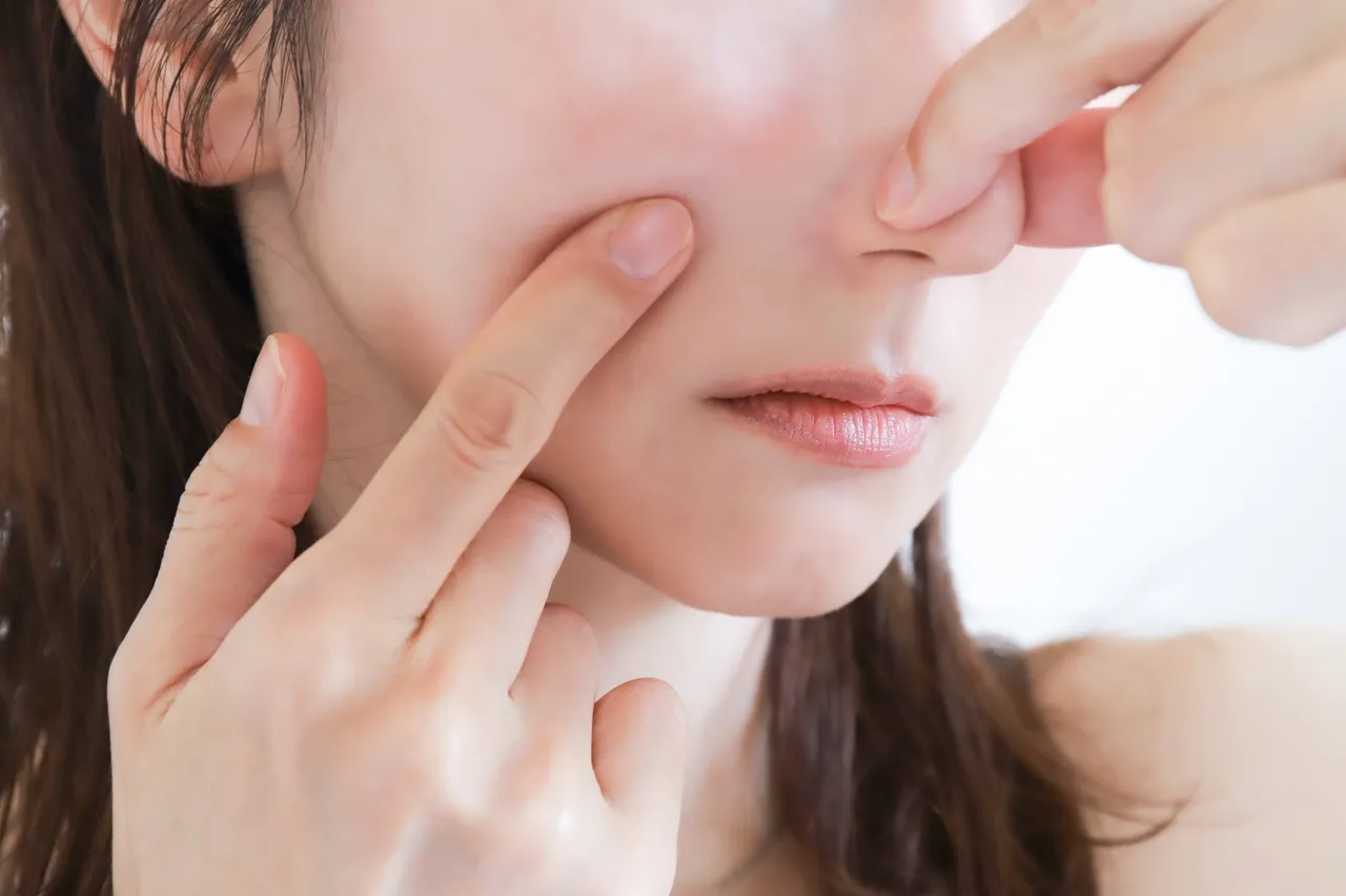 鼻筋と小鼻に指を当てる女性