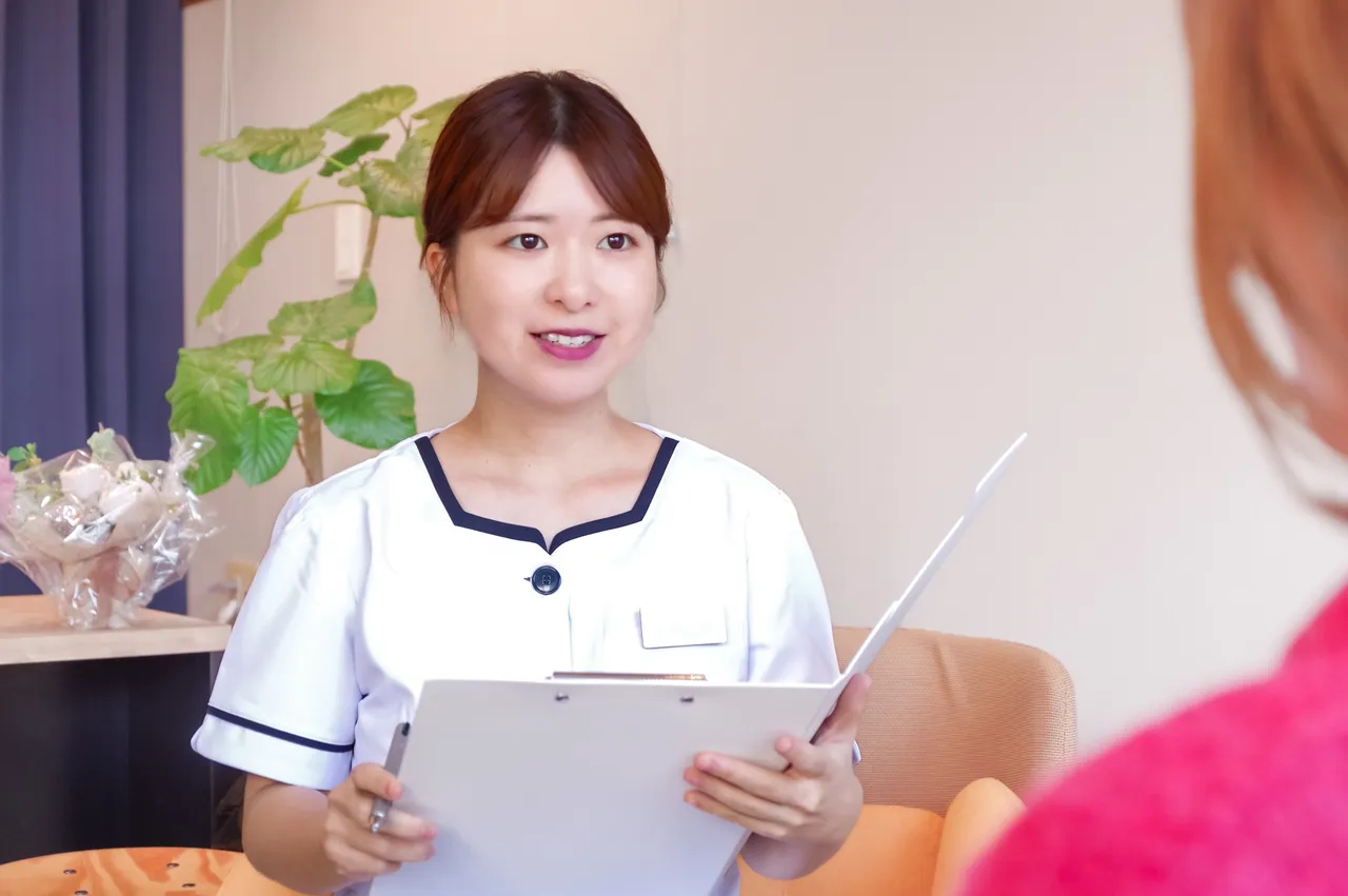 クリップボードを持ってカウンセリングをする女性スタッフ