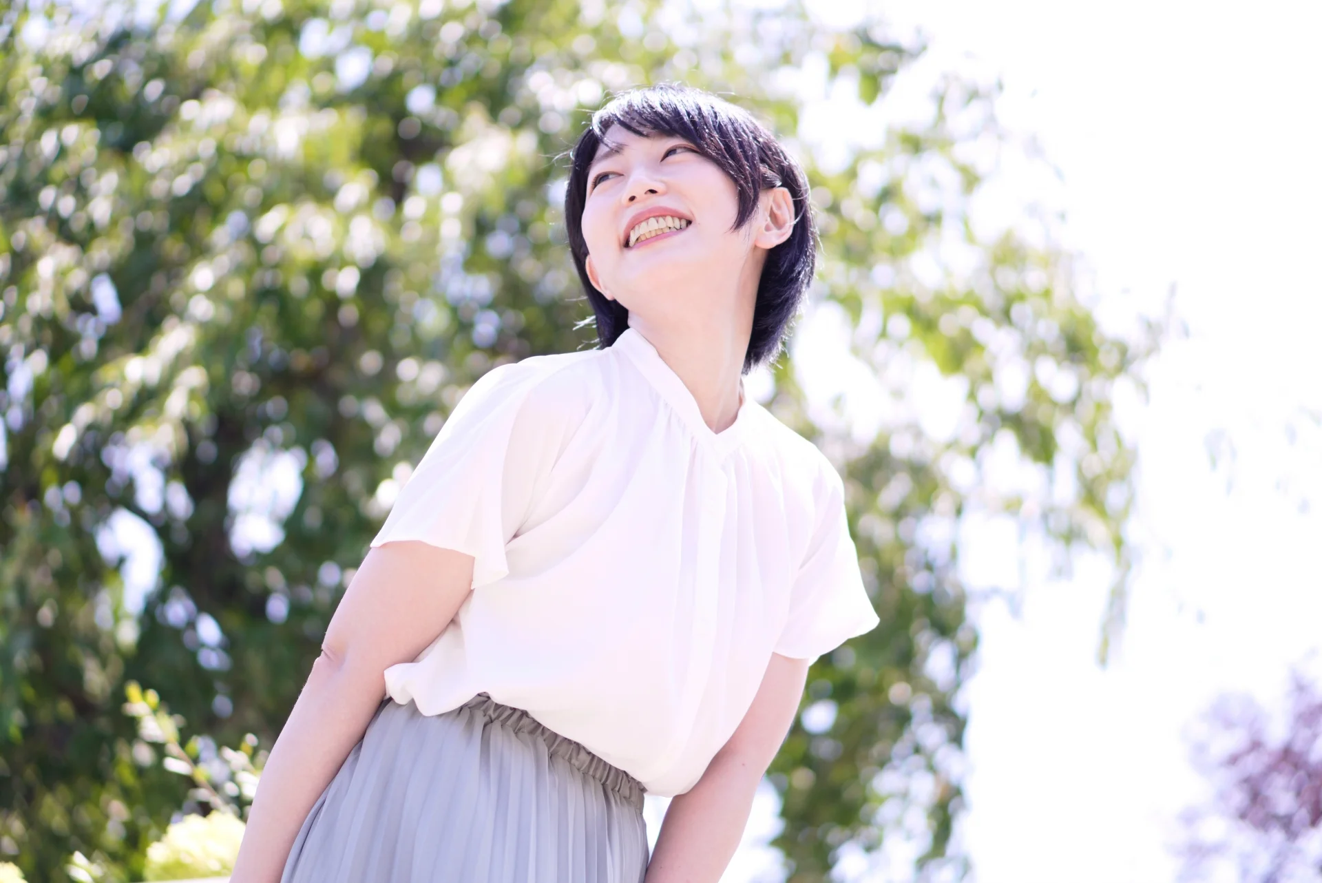 屋外で歯を見せて笑う女性