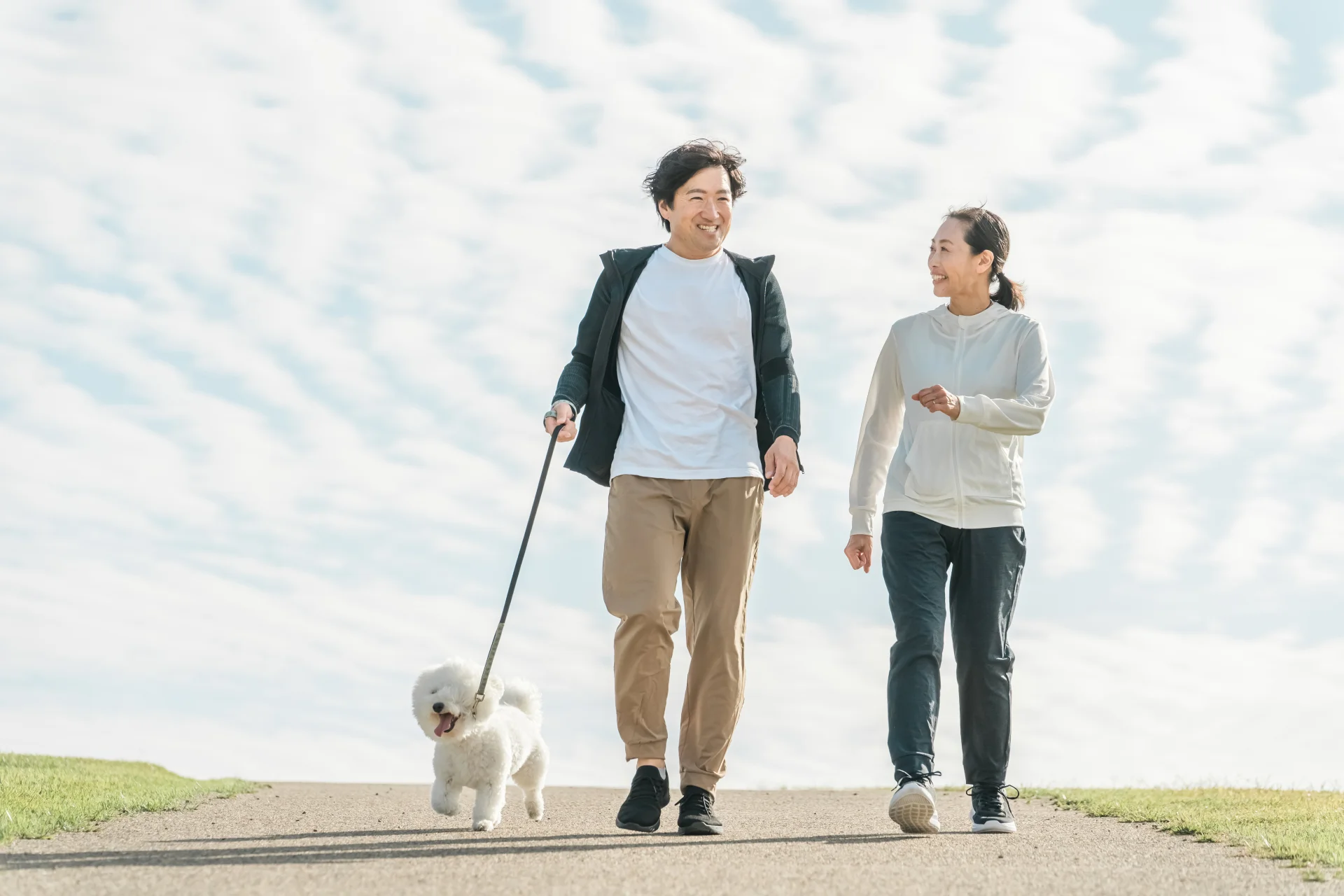 犬を連れて屋外を歩く男性と女性（歩いて体重を落とすイメージ）