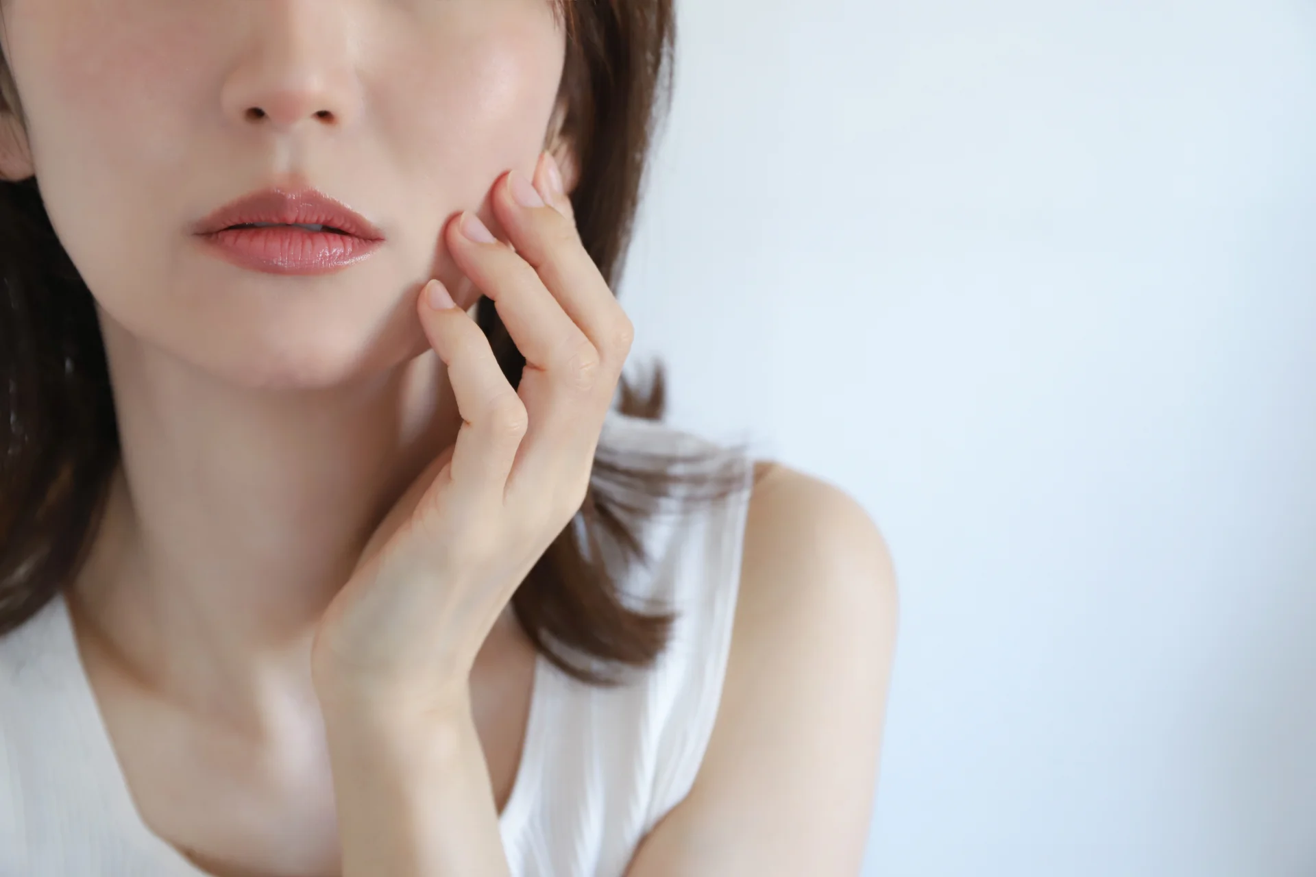 頬に指先を添えた女性の口元と頬のアップ（頬の変化を振り返るイメージ）